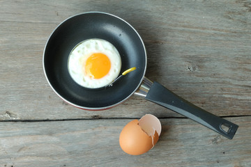 fried egg with pan on wood floor