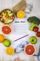 Food and sheet of paper with a diet plan on a  wooden table. Con