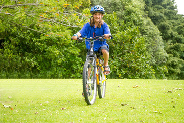 Naklejka premium young happy preteen child boy riding a bicycle on natural park b