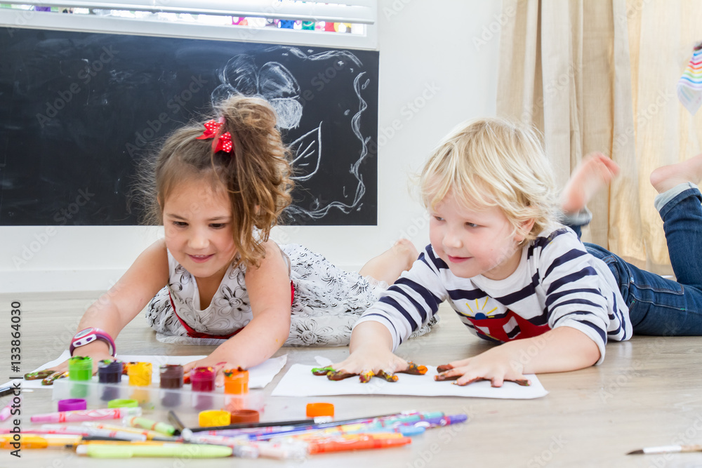 Wall mural Cute little preschooler children - boy and girl - drawing at hom