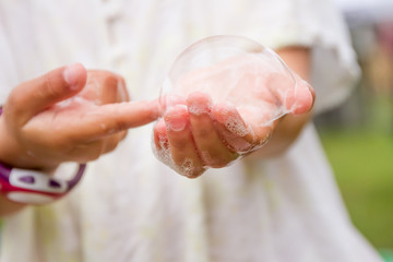 outdoor portrait of young happy child playing with soap bubbles