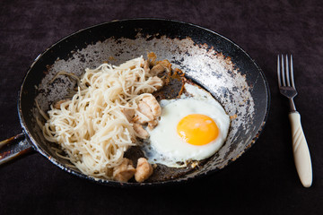 an old cast-iron frying pan with egg, pasta and fish