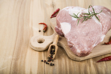 Raw pork with rosemary and spices on a wooden board on the table