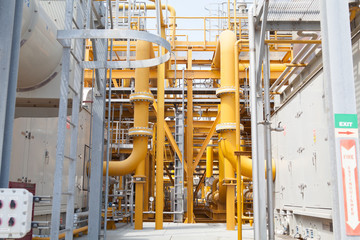 Many yellow pipes and huge cooling systems in open air constructed factory.