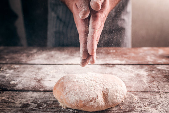 Man slap his hands above fresh bread closeup. Baker finishing his bakery, shake flour from his hands, free space for text. Homemade bakery, cooking process concept