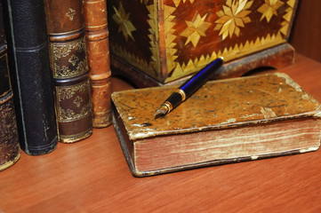 old books, jewelry box and a pen