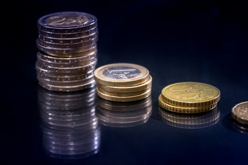 lot of euro coins with reflection on black table.