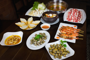 Set of Vietnamese seafood with Barbecue tiger shrimps, grilled sweet snail, bread slide, Spicy steam clam, and hot pot with vegetable and raw beef slide