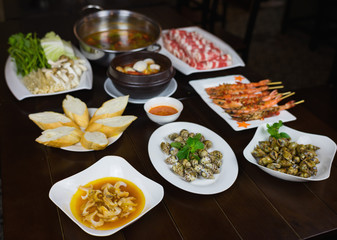 Set of Vietnamese seafood with Barbecue tiger shrimps, grilled sweet snail, bread slide, Spicy steam clam, and hot pot with vegetable and raw beef slide