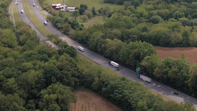 AERIAL: Loaded semi trucks on interstate shipping cargo on sunny summer day