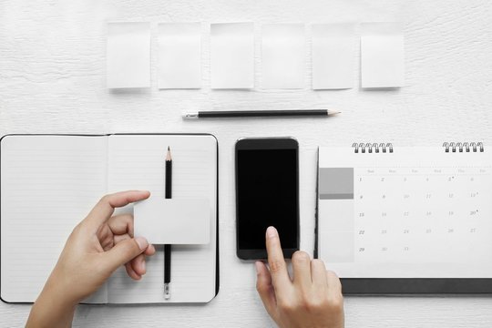 Hand touch on a mobile phone black screen. , Hand-Credit  in a notebook on a desk, top view.