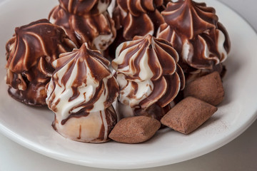 Chocolate chip cookies and three sweets on a white plate. Air biscuit has a beautiful shape. Brown - white cake