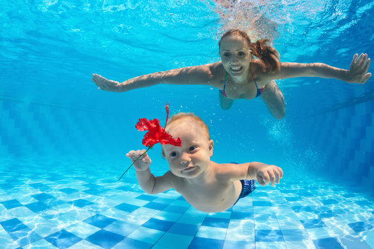 Family fitness - happy mother, active baby son learning swim, dive underwater with fun in pool. Active parents healthy lifestyle, water sport activities, kids aqua classes, children swimming lesson.