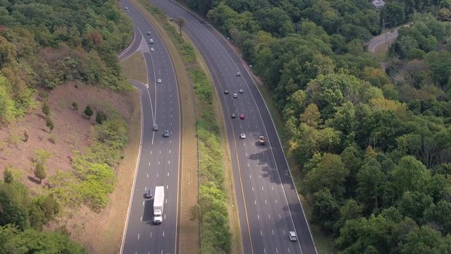 AERIAL: Semi trucks and personal cars rushing on interstate highway on sunny day