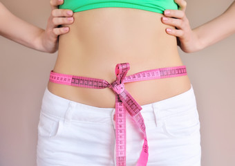 Woman measuring waist with tape on knot, dieting concept.