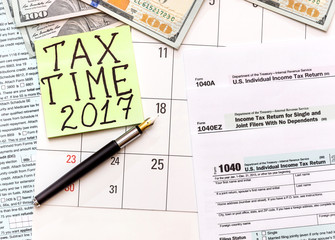 Sticker with words "TAX TIME 2017" with tax form 1040 and money
