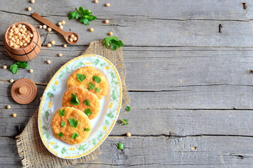 Roasted pea burgers on a plate and wooden table. Healthy diet cutlets cooked from peas and decorated with parsley. Old wooden background with empty place for text. Vegetarian food concept