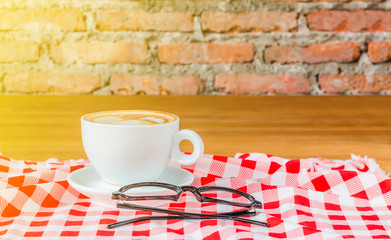 A cup of hot coffee on wood table with glasses