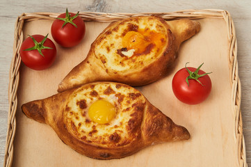 Traditional Georgian dish of cheese-filled fragrant bread on a wooden table. Adjaran open khachapuri.
