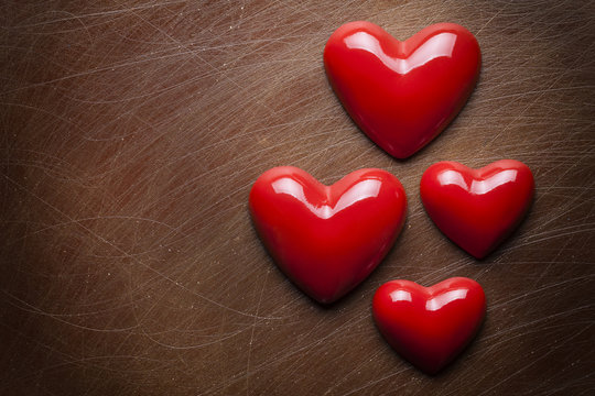 Four red hearts on brown scratched background