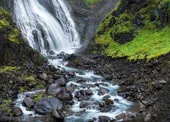 Fjordland, West Iceland - Waterfall tumbles into lush green vall