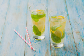 lemonade with mint on rocks served in a glass with a straw