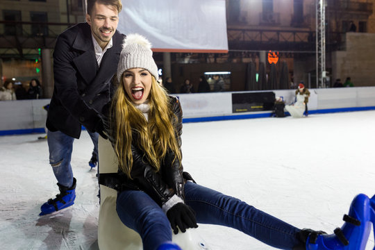 Beautiful Young Couple Ice Skating On Rink Outdoors.