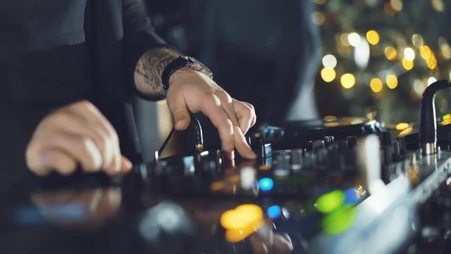 Hands of DJ tweak various track controls on dj's deck in 4K