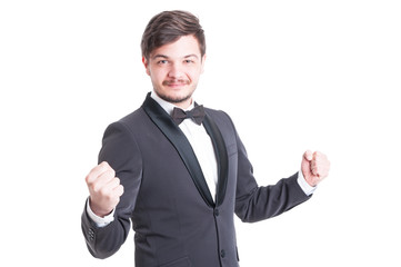 Handsome man wearing tuxedo and bowtie making success gesture