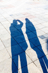 The shadows of three people on a pavement  tiles.