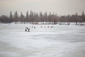 Fishermen on the ice near the fishing town in the evening