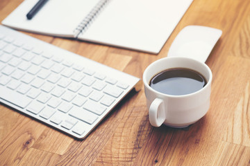 Coffee cup and keyboard computer notebook on wooden table background