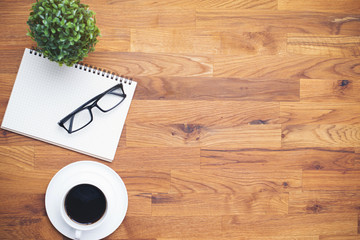 Coffee cup and notebook lens  on wooden table background