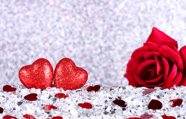 The red heart shapes and red rose flower on abstract light silver glitter background in love concept for valentines day and romantic moment