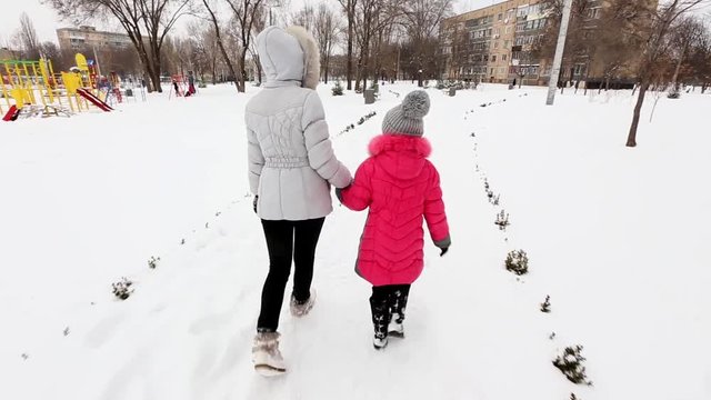 Two girls, mother and daughter, walking at a park in winter frosty day.
