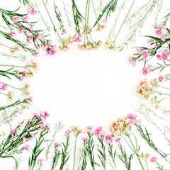 Round frame of colorful wildflowers, green leaves, branches on white background. Flat lay, top view. Valentine's background