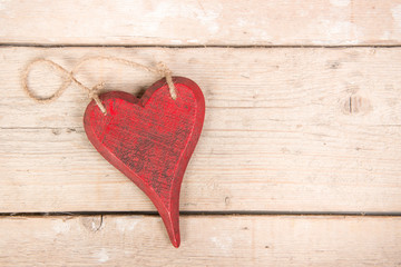Red wooden heart on a wooden background seen from above as wishing card with space for text