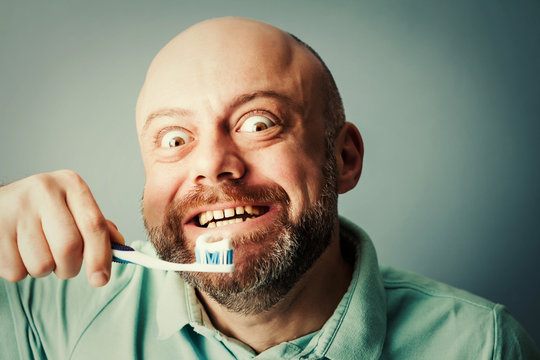 a bearded middle-aged man holding a toothbrush in his hand, brus