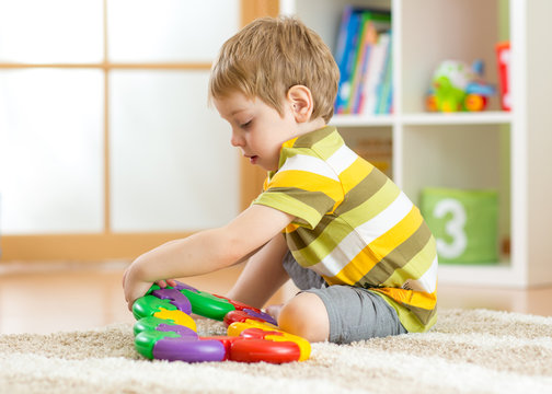 Kid little boy plays with a multi colored puzzle in nursery
