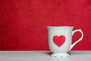 White mug with a heart on a red background