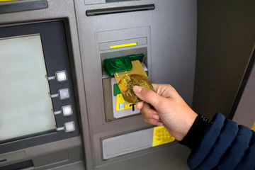 Woman inserts card in the ATM machine to withdraw money