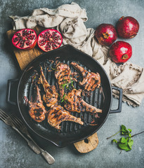 Barbecue dinner. Grilled lamb meat chops with onion and rosemary in black cast iron pan served with...