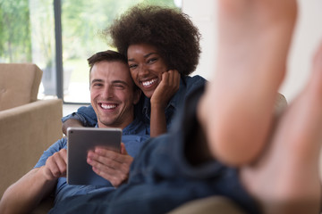 multiethnic couple relaxing at  home with tablet computers