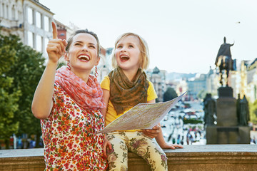 Naklejka premium mother and child travellers in Prague holding map and pointing
