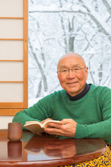 雪景色の見える和室でくつろぐシニア