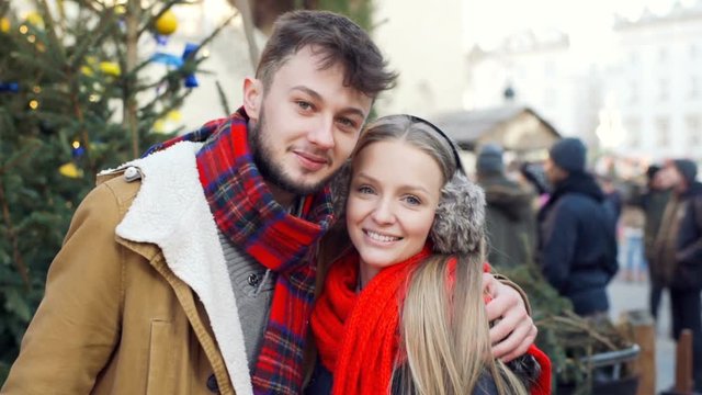 Couple cuddling and smiling to the camera at the christmas market, steadycam shot
