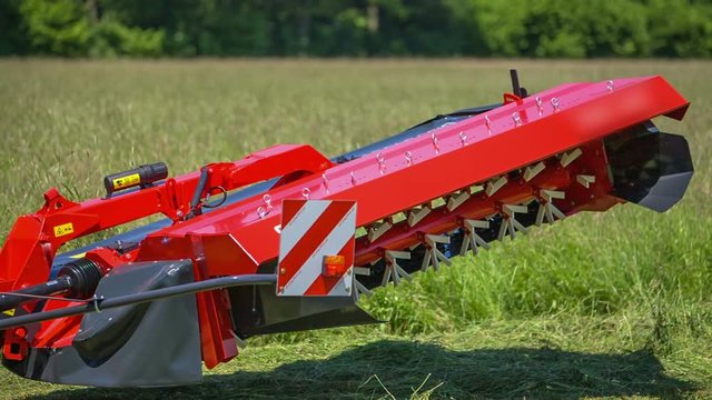 A grass cutting machinery is lowering down to the ground and a farmer will now start working in the fields.
