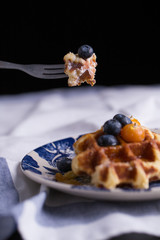 Blueberry waffle set in a nice dish and a fork cut in piece with black background copy space.