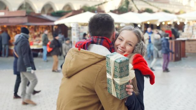 Boy gives his girlfriend christmas present and huggs her, steadycam shot
