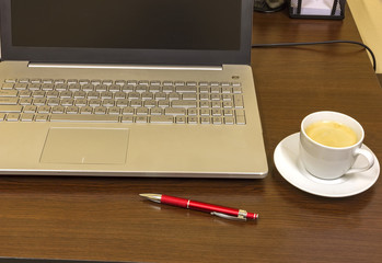 Comfortable working place in office with wooden table, laptop,pen and coffee